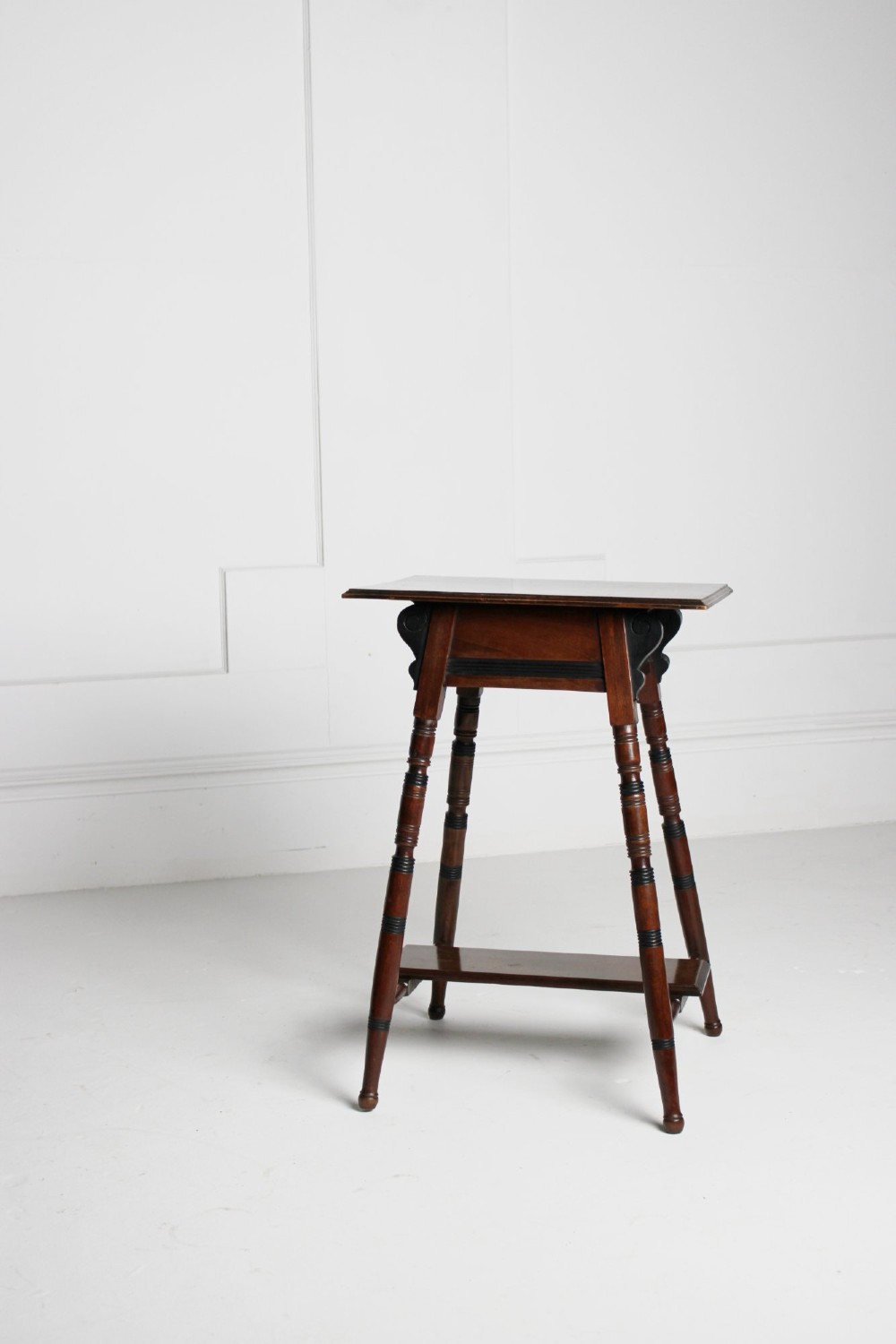 A tall rectangular dark mahogany lamp table featuring turned legs with ebonised bands, a lower undertier, and shaped corner brackets.