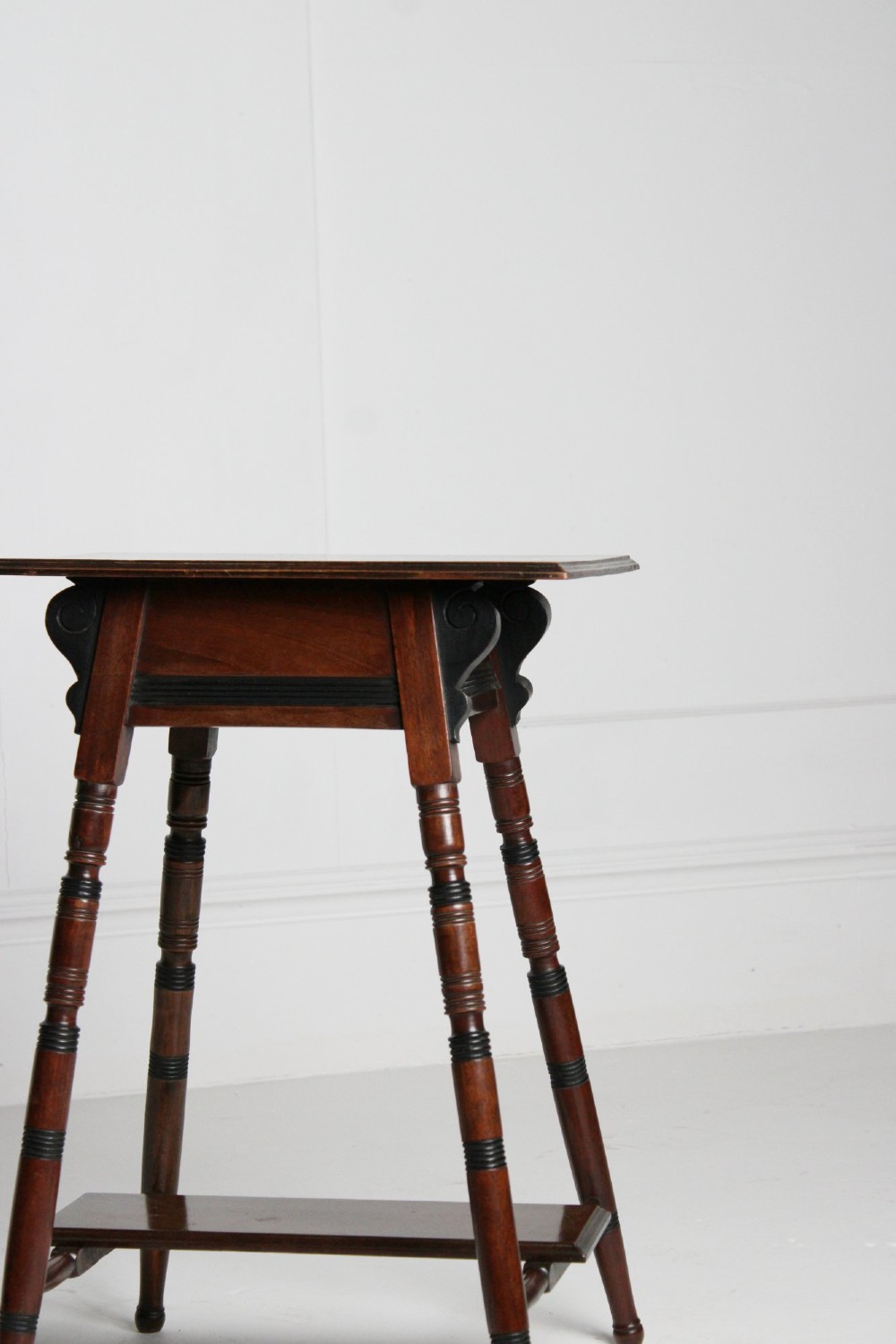 A tall rectangular dark mahogany lamp table featuring turned legs with ebonised bands, a lower undertier, and shaped corner brackets. View II