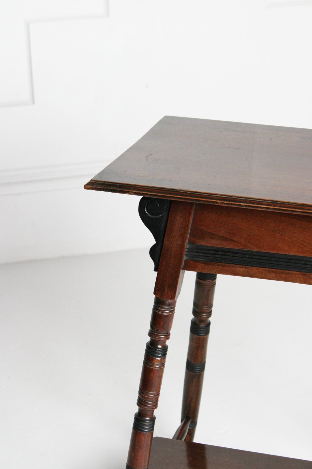 A tall rectangular dark mahogany lamp table featuring turned legs with ebonised bands, a lower undertier, and shaped corner brackets. View V