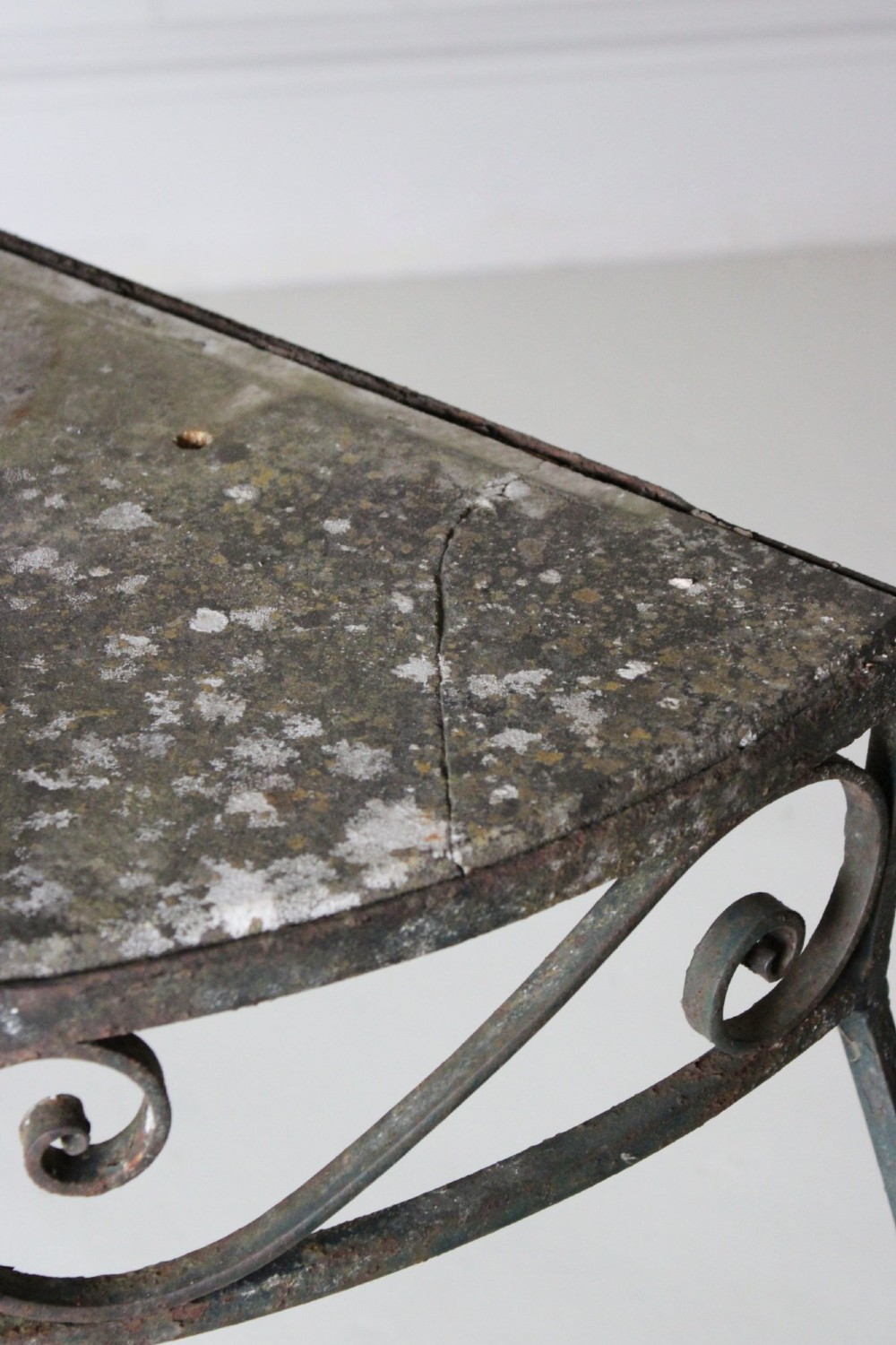 A demilune wrought iron console table featuring scrollwork decoration along the apron and a weathered dark marble top. View VII