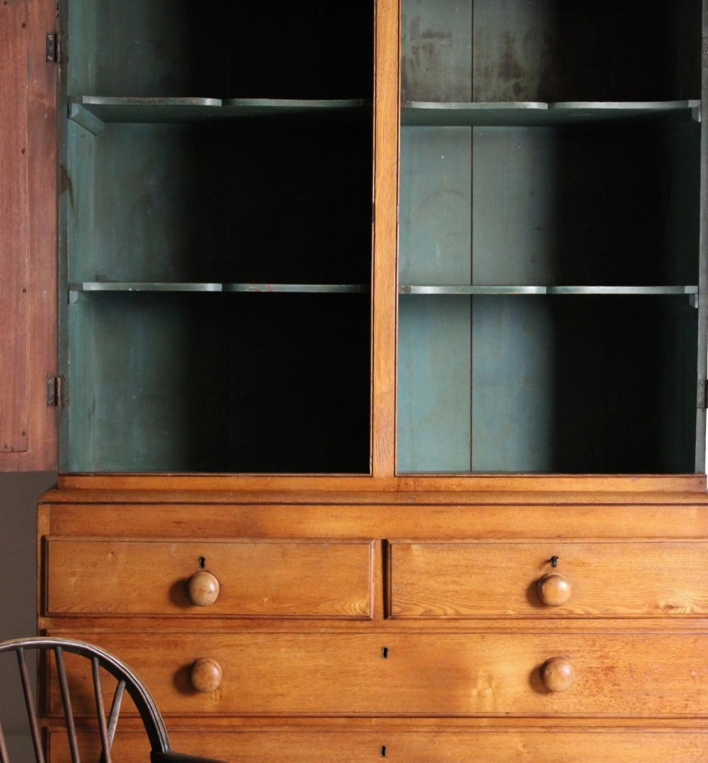 A 19th-century ash linen press featuring double cabinet doors open to reveal green-painted interior shelves over a chest of five drawers with turned wooden handles. View II