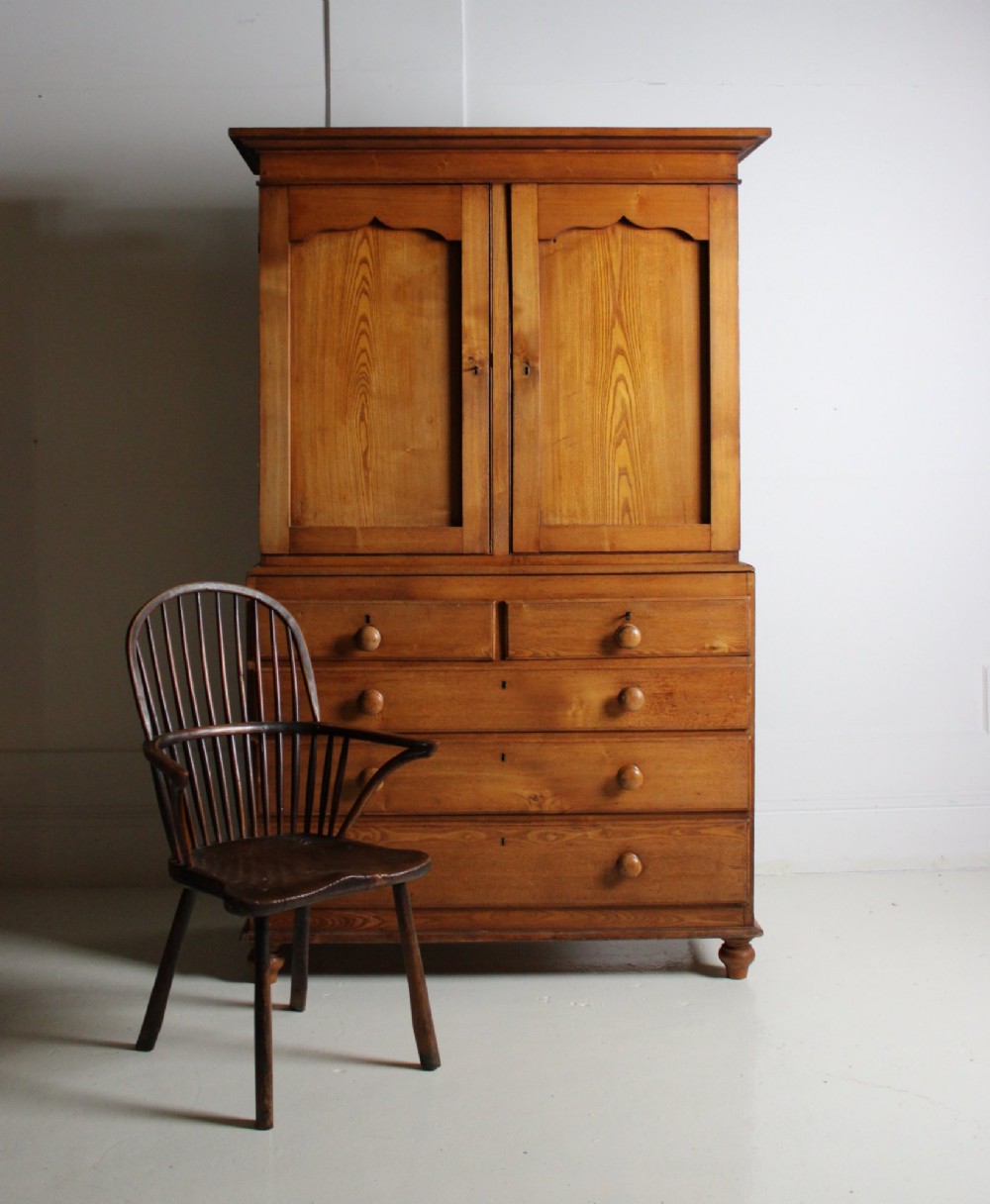 A 19th-century ash linen press featuring double cabinet doors open to reveal green-painted interior shelves over a chest of five drawers with turned wooden handles. View VI