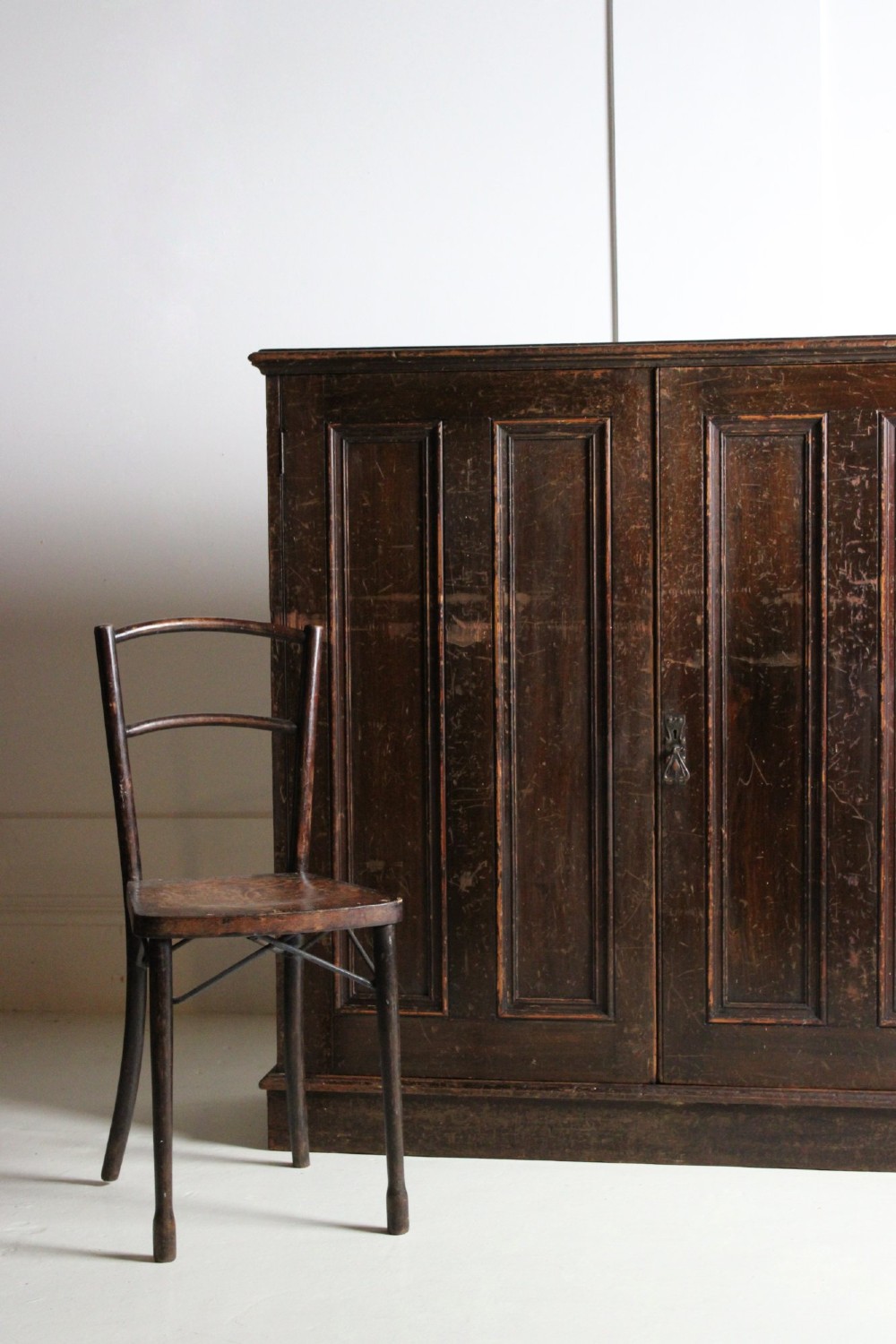 A 19th-century dark stained pine cupboard featuring double-panelled doors, a plinth base, and surface scratches. View II