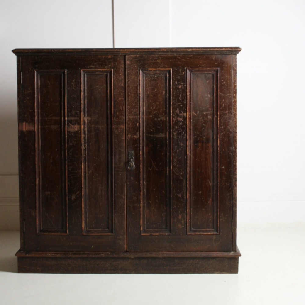 A 19th-century dark stained pine cupboard featuring double-panelled doors, a plinth base, and surface scratches. View III