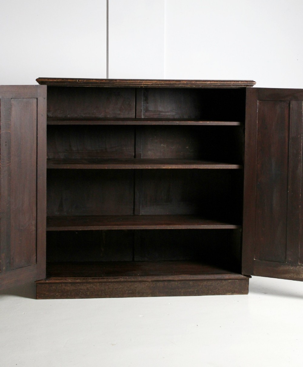 A 19th-century dark stained pine cupboard featuring double-panelled doors, a plinth base, and surface scratches. View IV