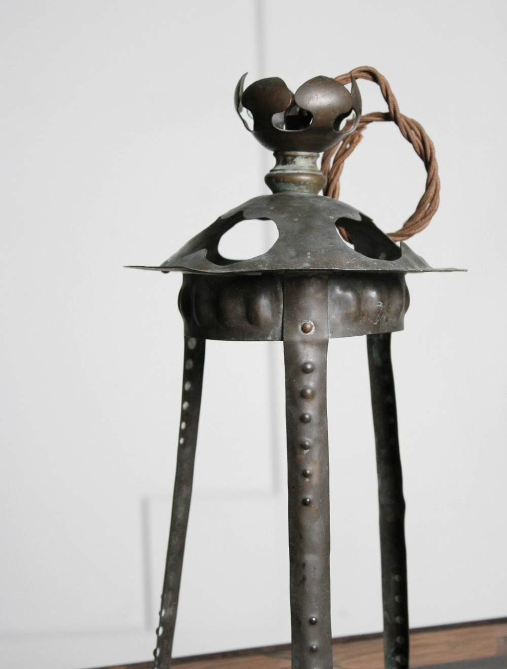 A hand-hammered Arts and Crafts copper porch lantern featuring riveted vertical straps, cut-out vents on the dome top, and a flower-shaped finial. View IV