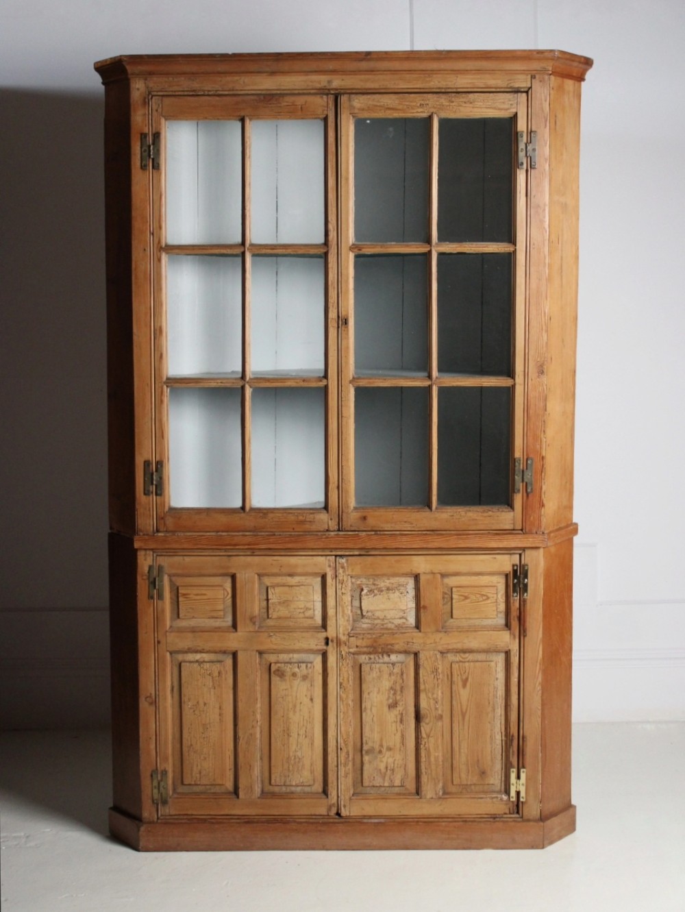 A tall freestanding pine corner cupboard featuring a glazed upper display section with multi-pane glass doors above a two-door lower cabinet with raised timber panels. View II