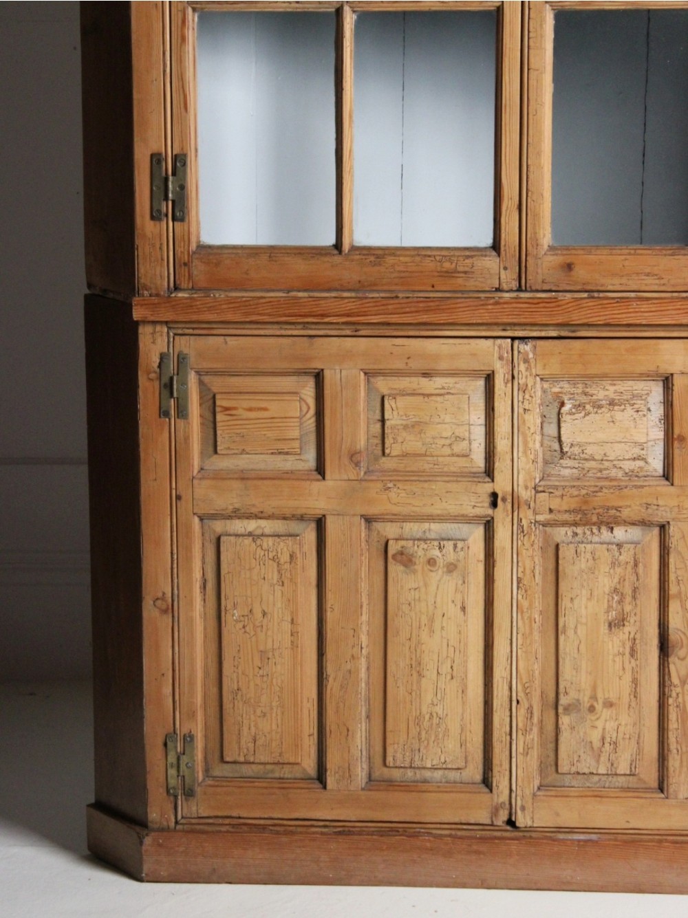 A tall freestanding pine corner cupboard featuring a glazed upper display section with multi-pane glass doors above a two-door lower cabinet with raised timber panels. View V
