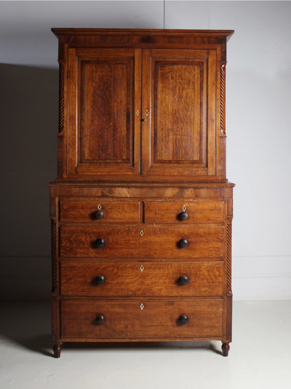 A large Georgian oak housekeepers cupboard featuring an upper two-door cabinet with raised panel doors atop a lower chest of drawers with turned wooden knobs. View II