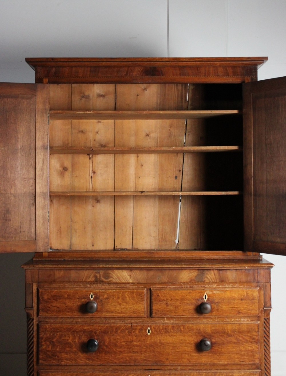 A large Georgian oak housekeepers cupboard featuring an upper two-door cabinet with raised panel doors atop a lower chest of drawers with turned wooden knobs. View IV