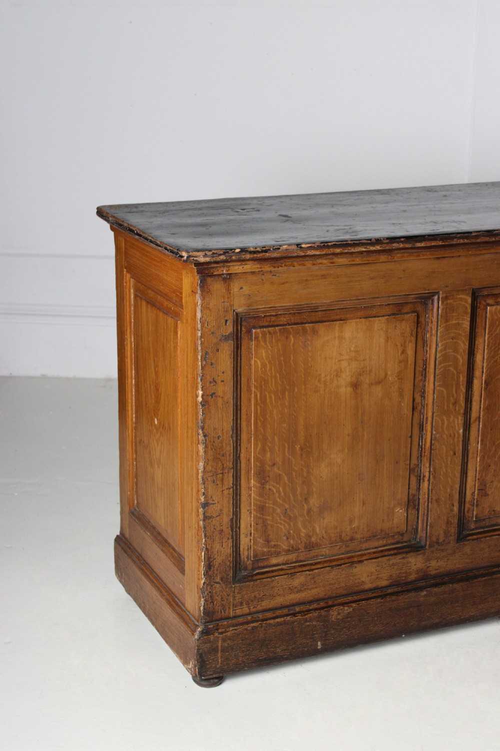 A Victorian painted pine shop counter featuring a scumbled faux oak finish, two large recessed front panels, and a low plinth base. View II