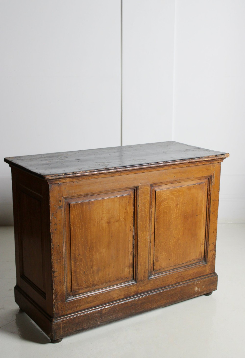 A Victorian painted pine shop counter featuring a scumbled faux oak finish, two large recessed front panels, and a low plinth base. View III