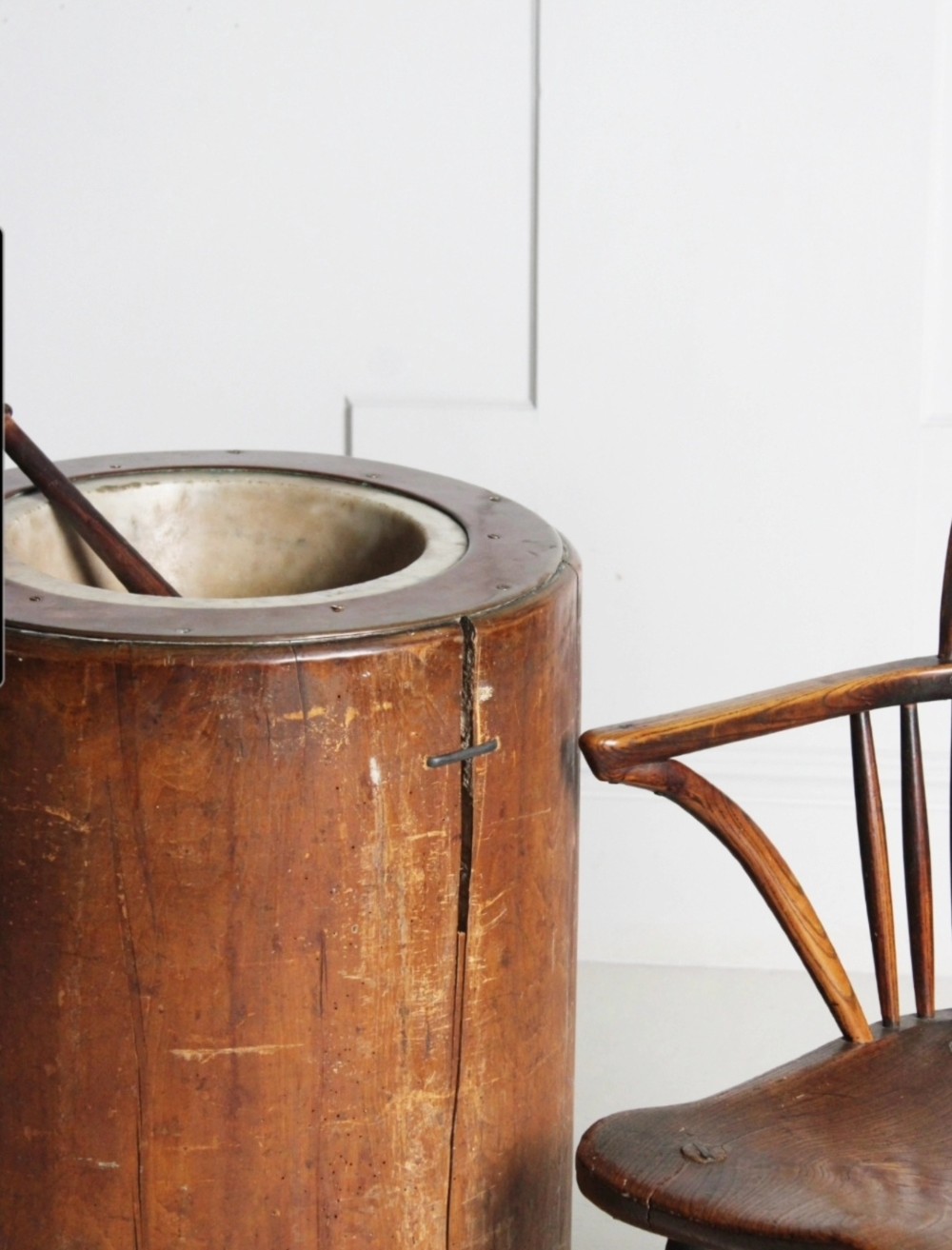 A late 19th-century floor-standing wooden mortar constructed from a hollowed trunk section with an inset stone basin and a pestle. View II