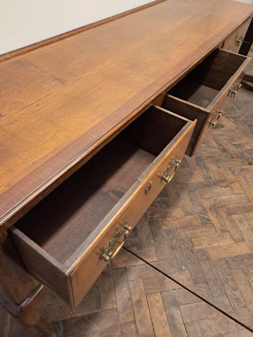fig 1. A Georgian oak dresser base featuring three drawers with brass swan-neck handles, a shaped apron, and cabriole legs.