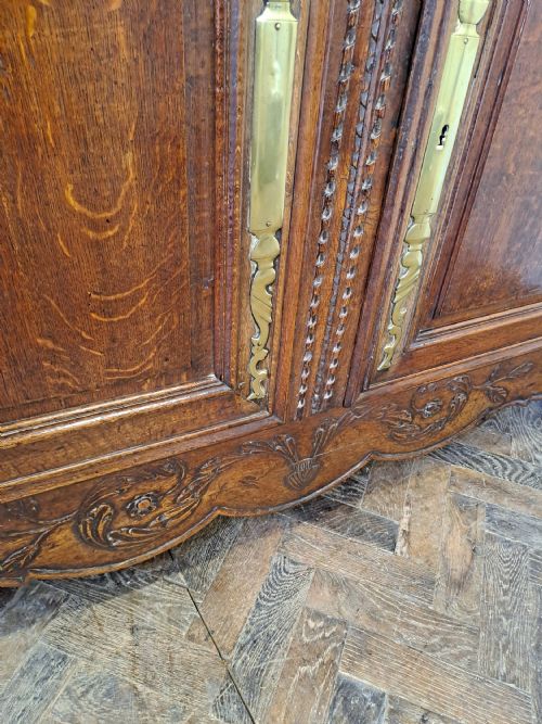 fig 1. A carved dark oak French provincial buffet base featuring two relief-carved cupboard doors with long brass hinges below two drawers.