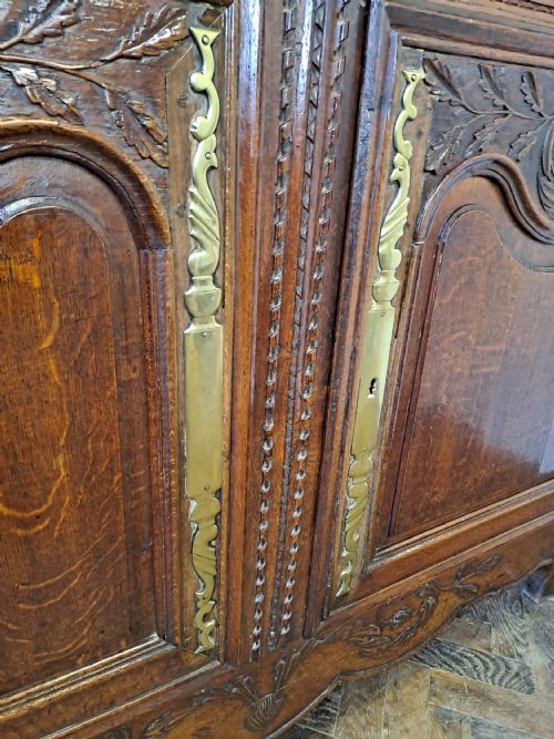 fig 2. A carved dark oak French provincial buffet base featuring two relief-carved cupboard doors with long brass hinges below two drawers.