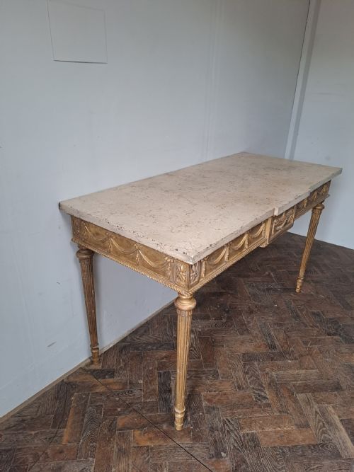 fig 1. A French Louis XVI style giltwood console table with a cream marble top, featuring carved swags, an urn motif, and four fluted legs.