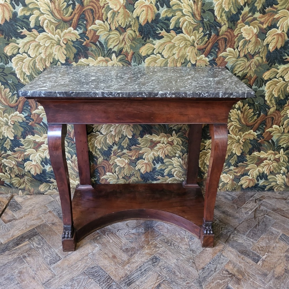 A 19th-century French mahogany console table featuring a grey marble top, S-curved front legs with carved feet, and a concave lower shelf.