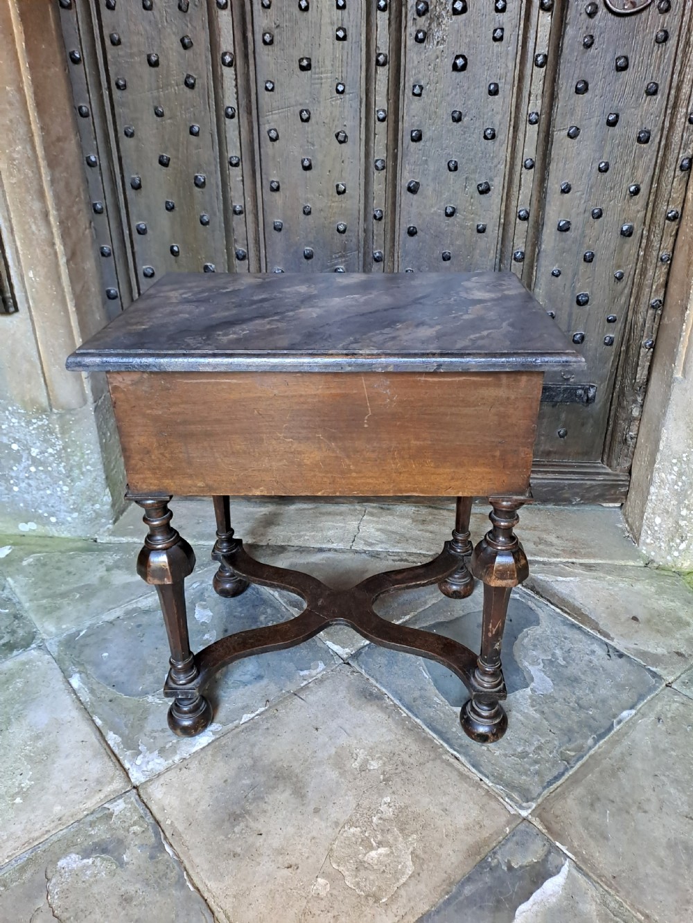 A walnut side table featuring three drawers with brass handles, inverted cup turned legs, and a curved X-stretcher. View V