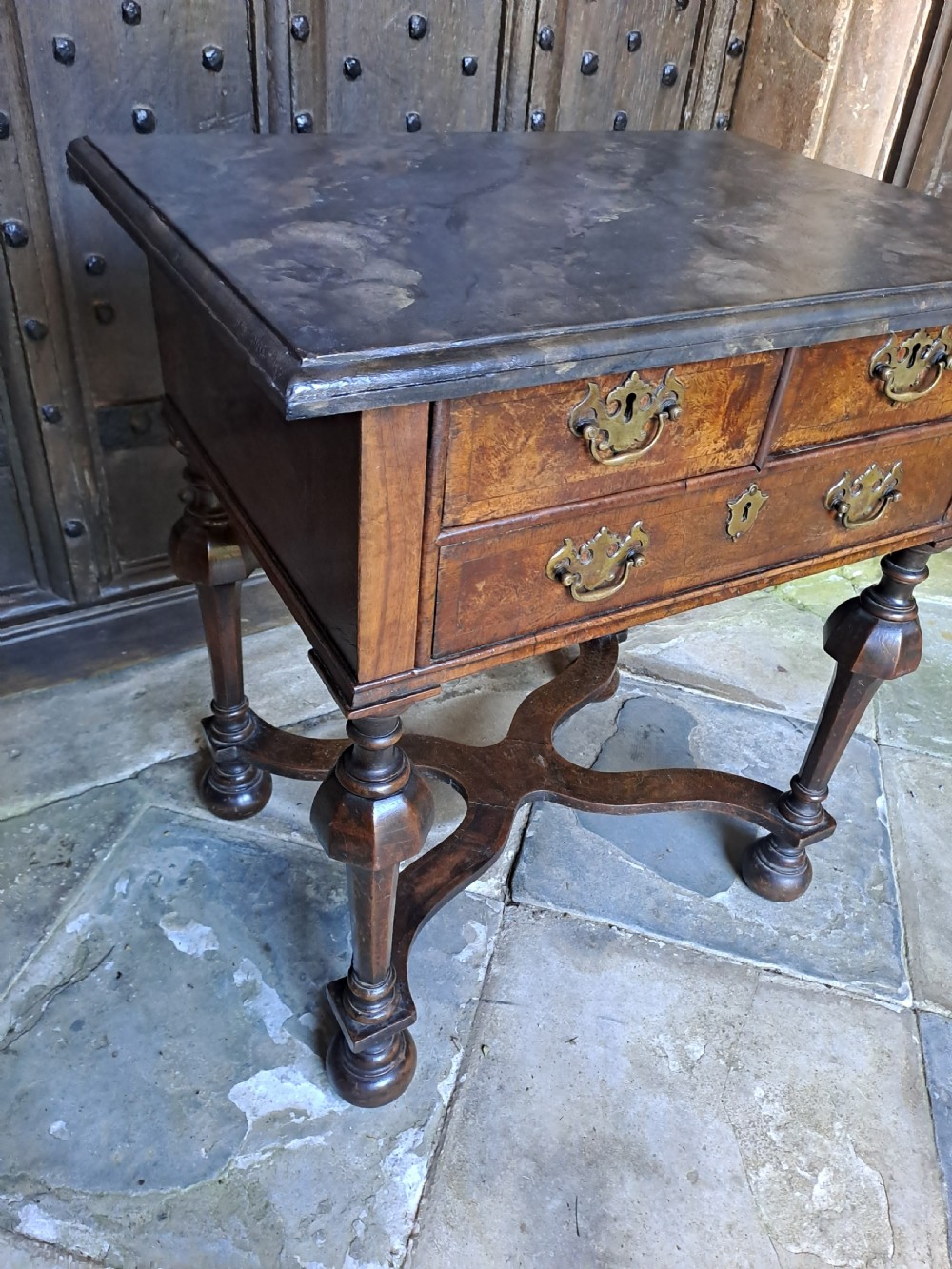 A walnut side table featuring three drawers with brass handles, inverted cup turned legs, and a curved X-stretcher. View II