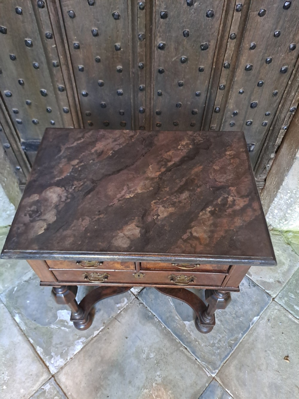 A walnut side table featuring three drawers with brass handles, inverted cup turned legs, and a curved X-stretcher. View IV