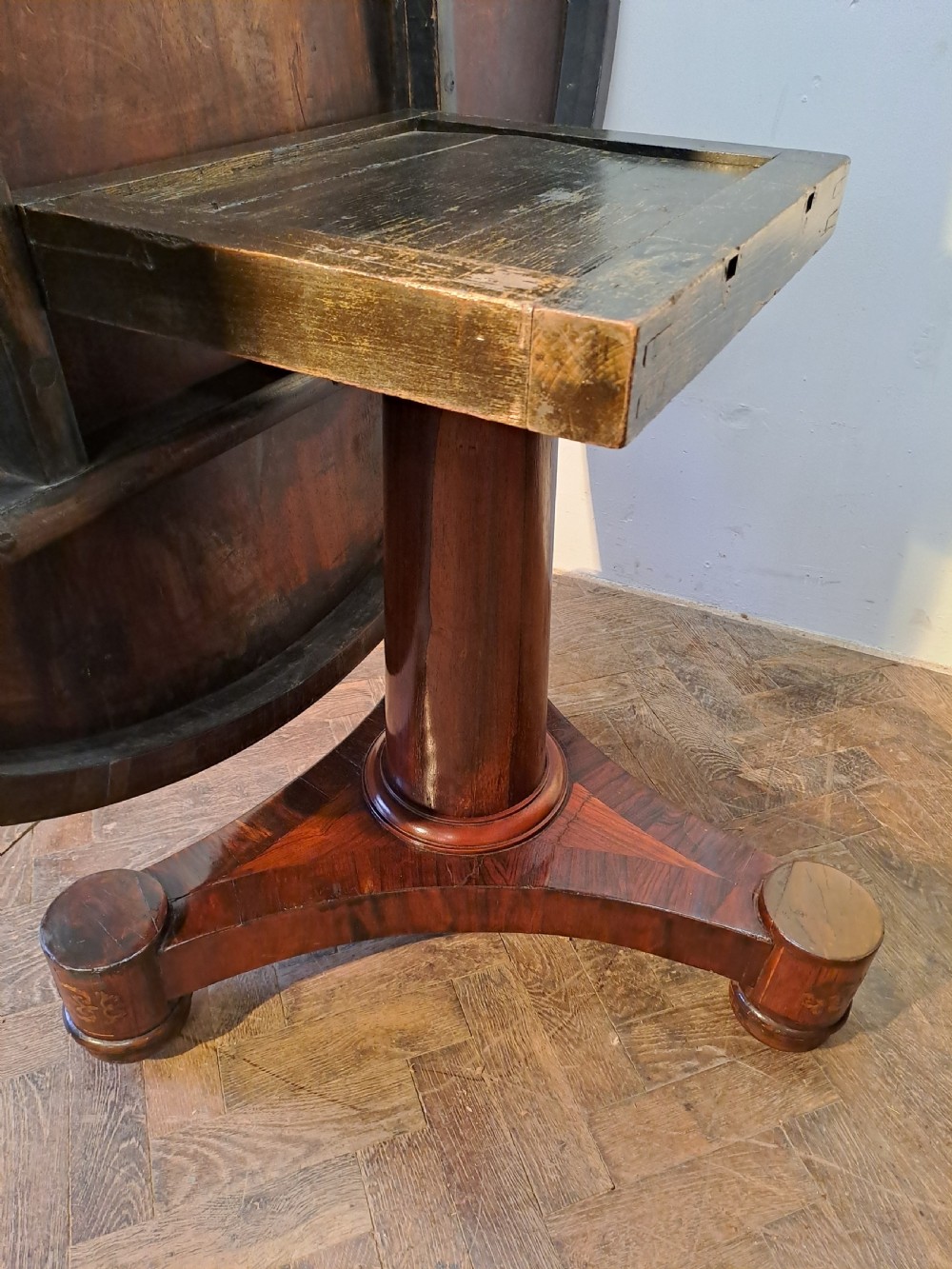 A Regency circular rosewood centre table shown tilted vertically, featuring floral brass marquetry inlay along the perimeter and base. View VII