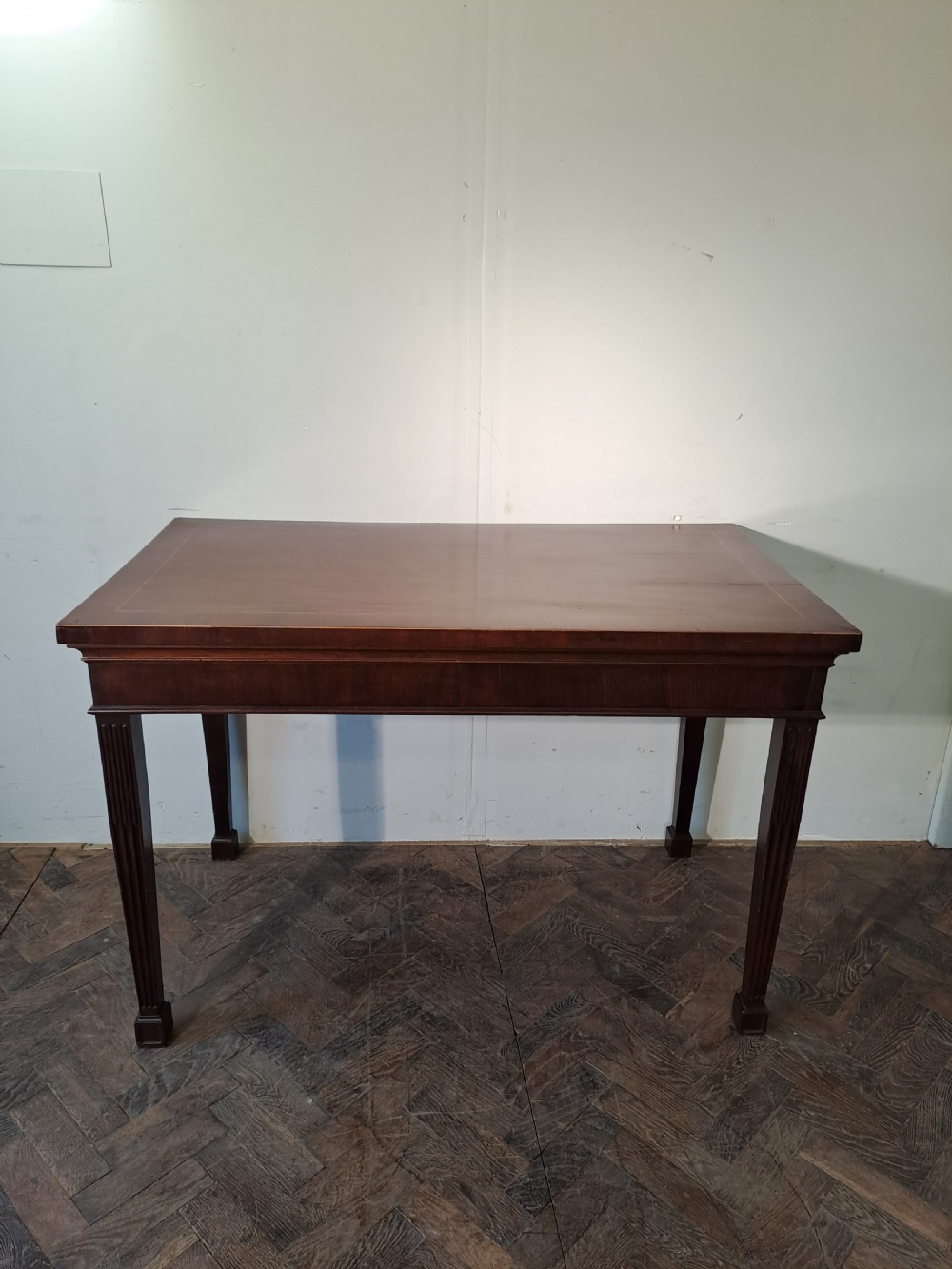 A Georgian dark mahogany rectangular console table featuring fluted square tapered legs and subtle top line inlay.