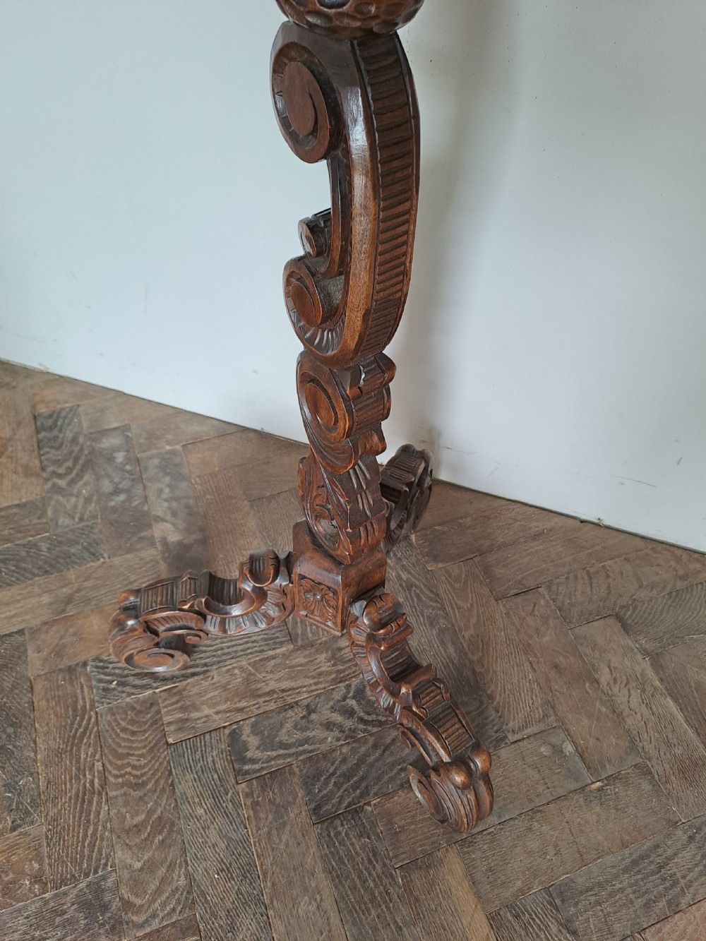 A dark brown carved wood tripod table featuring an ornate scalloped rim top, a detailed central pedestal, and three scrolled legs. View IV