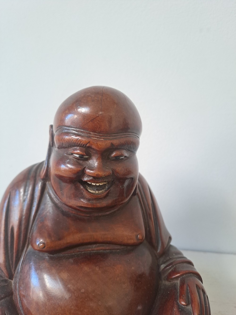 A pair of hand-carved warm brown wooden figures depicting seated, smiling Chinese Laughing Buddhas. View VI