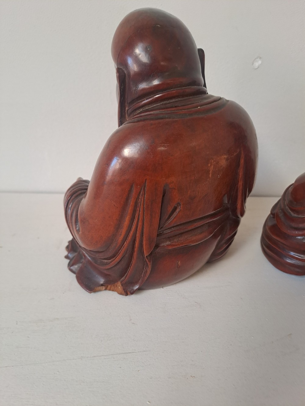 A pair of hand-carved warm brown wooden figures depicting seated, smiling Chinese Laughing Buddhas. View IV