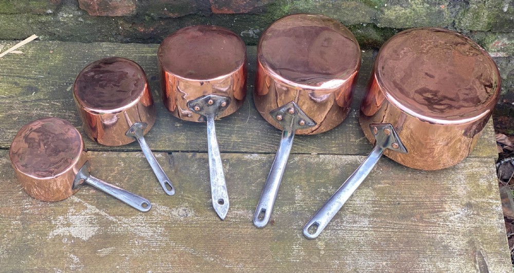A harlequin set of 5 copper saucepans some with makers marks one for Harrods 