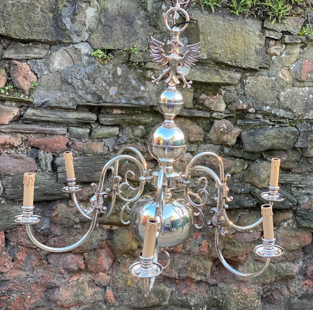 A six-arm silver-plated brass Dutch-style chandelier featuring a cresting eagle finial, baluster stem, spherical base drop, and candle-style light sockets. View II