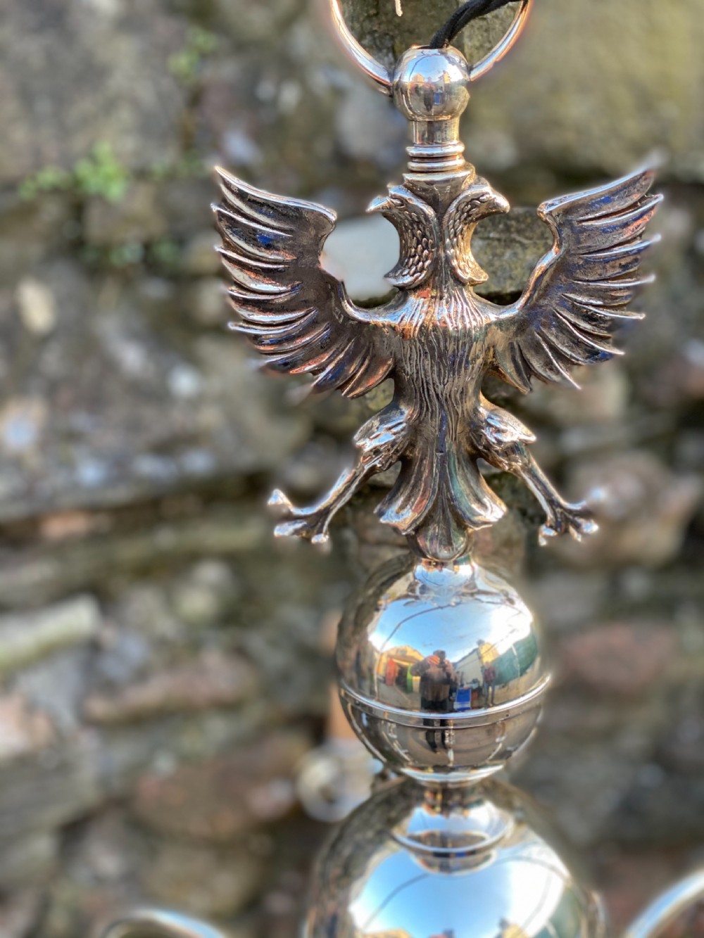 A six-arm silver-plated brass Dutch-style chandelier featuring a cresting eagle finial, baluster stem, spherical base drop, and candle-style light sockets. View III