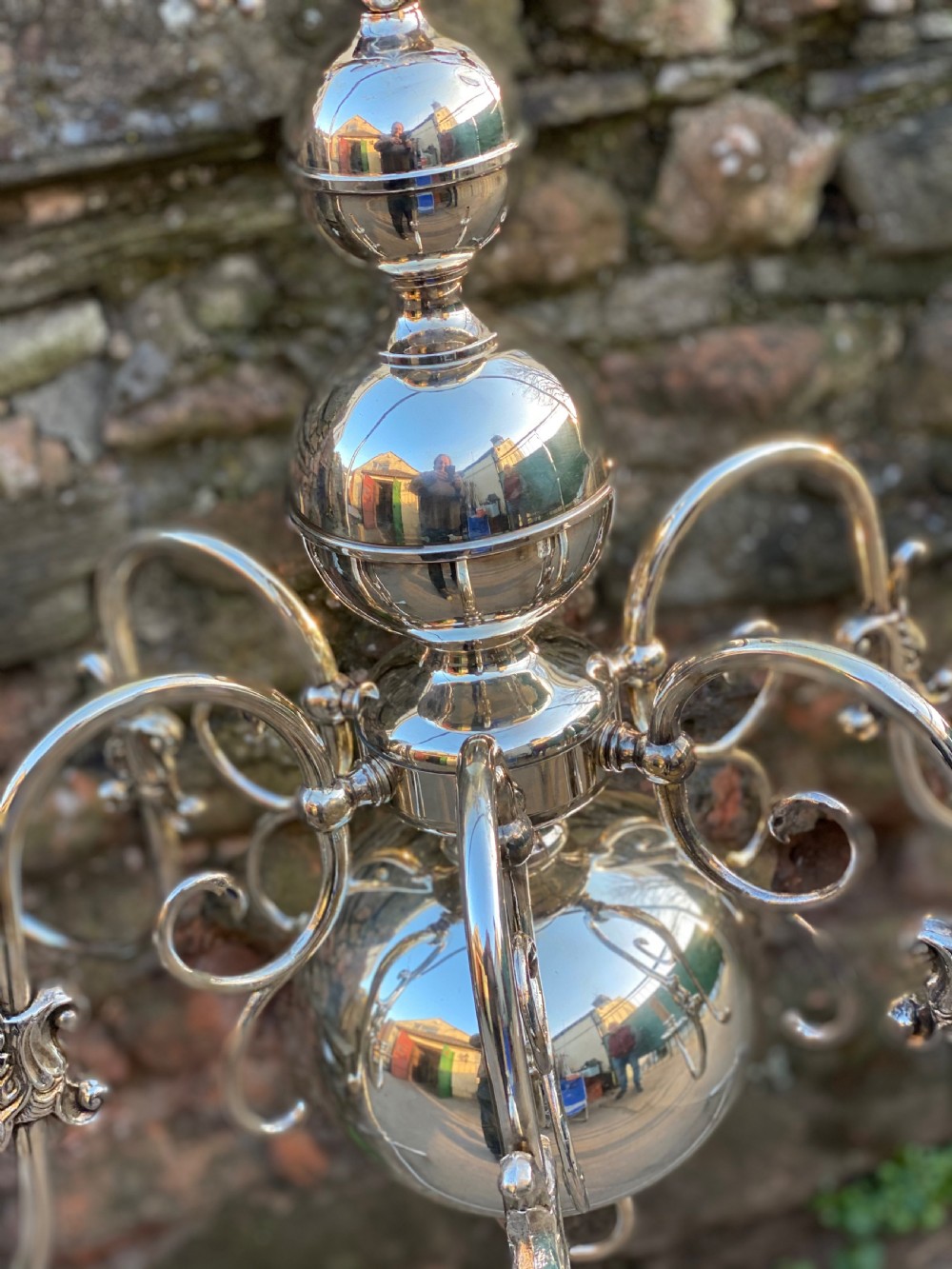 A six-arm silver-plated brass Dutch-style chandelier featuring a cresting eagle finial, baluster stem, spherical base drop, and candle-style light sockets. View V