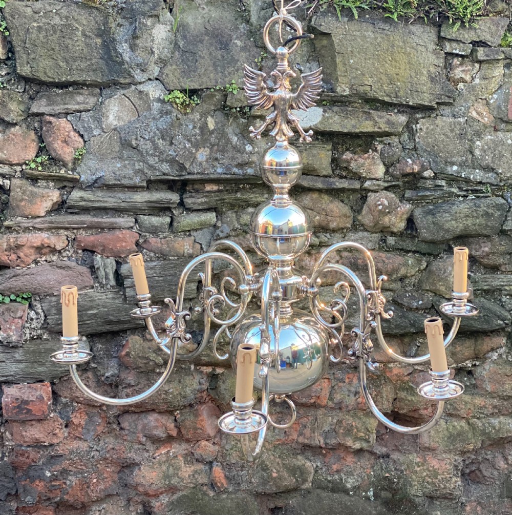 A six-arm silver-plated brass Dutch-style chandelier featuring a cresting eagle finial, baluster stem, spherical base drop, and candle-style light sockets. View VI
