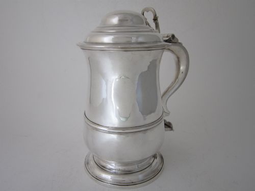 fig 1. An antique George III sterling silver lidded tankard featuring a moulded dome lid, scroll handle, central girdle band, and spreading base.