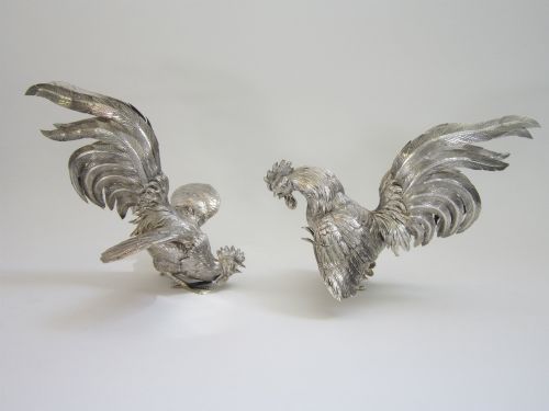 fig 1. A pair of detailed sterling silver figures depicting fighting cockerels with open wings and realistic feather textures.