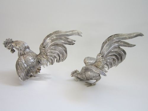 fig 2. A pair of detailed sterling silver figures depicting fighting cockerels with open wings and realistic feather textures.