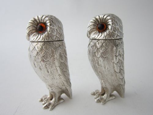 fig 1. A pair of cast sterling silver salt and pepper shakers in the form of standing owls with textured feather detailing and dark amber glass eyes.