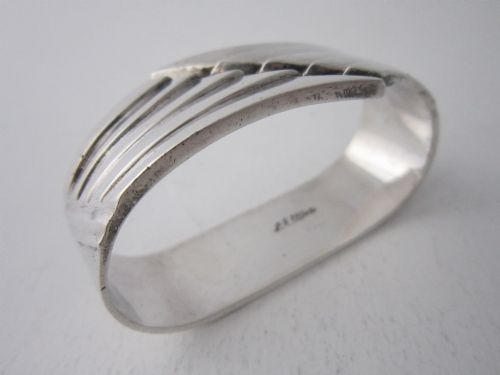 fig 1. A sterling silver napkin ring crafted in 1949 with an asymmetrical geometric motif featuring grooved stepped lines.