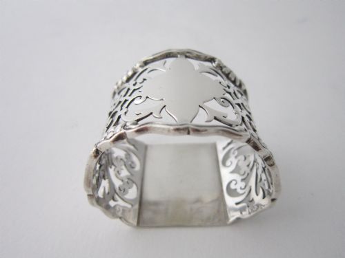 fig 1. An antique George V sterling silver napkin ring featuring intricate pierced scrollwork and a blank central cartouche.