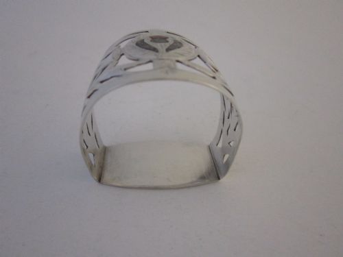 fig 1. A pierced sterling silver napkin ring featuring engraved Scottish thistle motifs and a central inlaid agate stone.