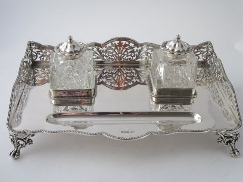 fig 1. A George V sterling silver tray featuring a pierced gallery, scroll feet, a central pen recess, and two square cut-glass inkwells with silver lids.