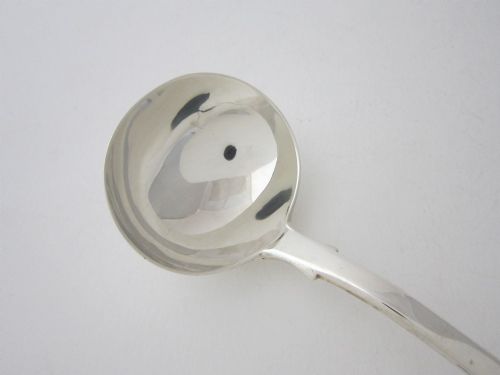 fig 1. A Victorian sterling silver sauce ladle featuring a fiddle pattern handle and a round deep bowl, displayed on a plain white surface.