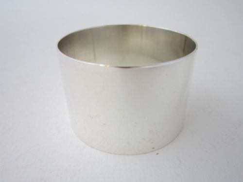 fig 1. A plain, highly polished circular sterling silver napkin ring resting upright on a white surface.