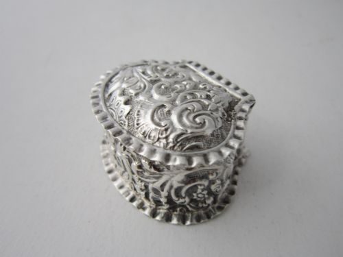 fig 1. An oval Victorian sterling silver pill box decorated with embossed scrollwork and crimped fluted rims on the lid and base.