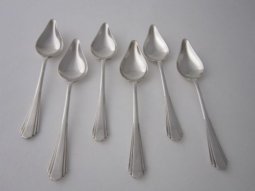 fig 1. A set of six Art Deco sterling silver grapefruit spoons with pointed bowls and stepped handles displayed in an open presentation case.