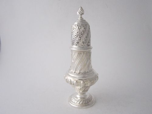 fig 1. A Victorian sterling silver sugar caster featuring a spirally fluted pierced dome lid, a flame finial, and embossed cartouche detailing on a pedestal foot.