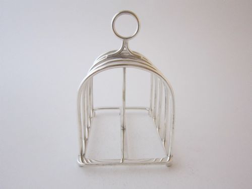 fig 1. A Victorian sterling silver toast rack with five arched wire partitions, a top ring handle, and small ball feet.