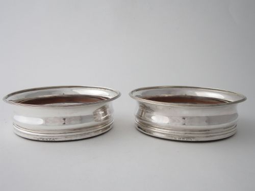 fig 1. A pair of circular George III sterling silver wine coasters with turned wooden bases and central silver bosses, displayed against a light grey background.